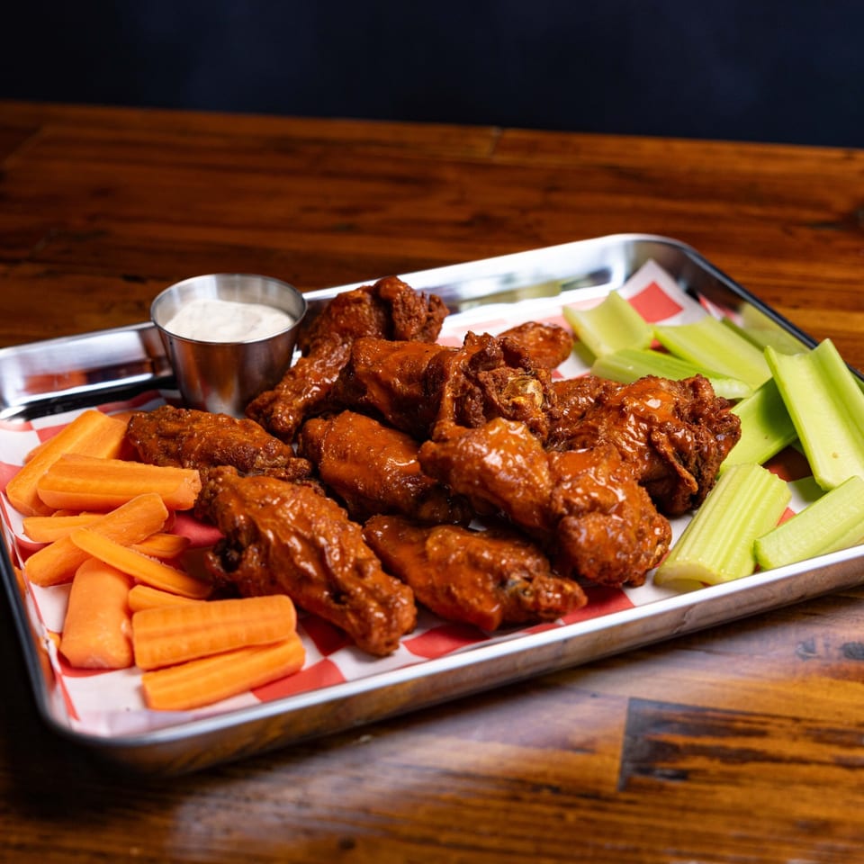 Sauced wings with carrots, celery, and dipping sauce.