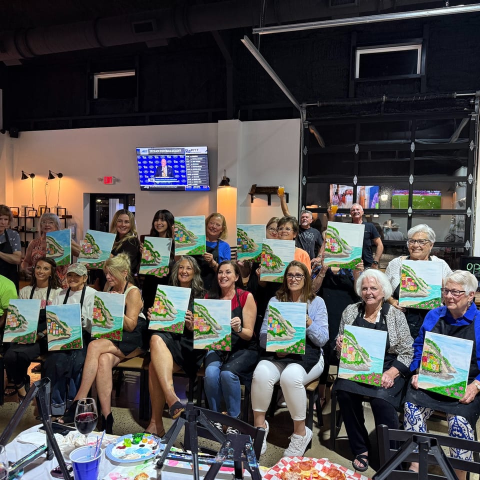 Paint night guests holding their finished paintings.